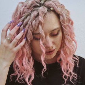 May include: A woman with pink curly hair and a nose ring is wearing a black t-shirt with the word "SMILEY" printed on it.