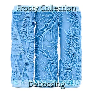 Peut inclure: Trois rouleaux en plastique bleu avec des motifs en relief différents. Les motifs représentent des scènes hivernales, notamment des sapins et des branches. Le texte "Frosty Collection" et "Debossing" est imprimé sur les rouleaux.