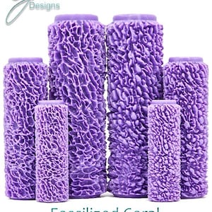 May include: Set of five purple textured paint rollers with a deep, fossilized coral design. The rollers are arranged in order of size, with the largest roller in the back and the smallest roller in the front. The text "Fossilised Coral Ultra Deep Texture" is printed below the rollers.