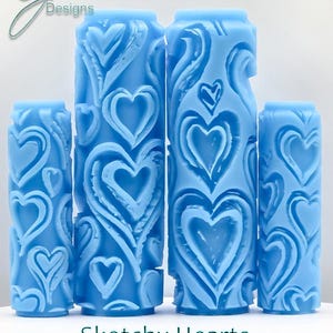 Peut inclure: Ensemble de quatre rouleaux de peinture bleus avec un motif de cœurs esquissés en relief profond. Les rouleaux sont de tailles différentes. Le texte "Sketchy Hearts Deep Texture" est imprimé sous les rouleaux.