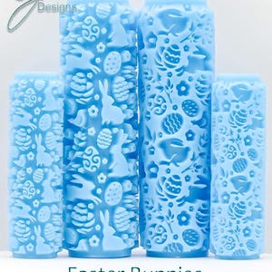 May include: Four light blue rolling pins with Easter designs. The pins have embossed patterns of bunnies, eggs, and flowers. The text "Easter Bunnies Deep Texture" is below the pins. The rolling pins are for baking.