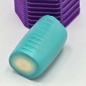May include: A teal and white polymer clay cane with a swirl pattern. The cane is cylindrical and has a smooth surface.