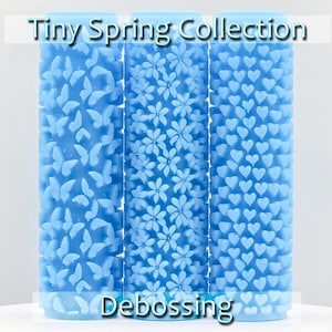 May include: Three blue silicone rollers with different embossed patterns: butterflies, flowers, and hearts. The rollers are labeled "Tiny Spring Collection" and "Debossing".