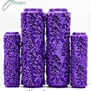 May include: Four purple, cylindrical candles with a floral design. The candles are of varying heights and feature an ultra-deep impression of bluebonnet flowers. The text "Blue Bonnets Ultra Deep Impression" is at the bottom.