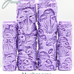 Puede incluir: Cuatro rodillos de pintura texturizados de color morado con un diseño de champiñones. Los rodillos están dispuestos verticalmente, con el rodillo más grande en la parte superior y el más pequeño en la parte inferior. El texto "Mushrooms Deep Texture" está impreso debajo de los rodillos.