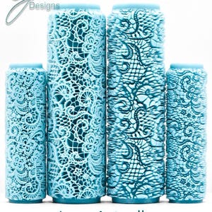 Op de afbeelding: Vier lichtblauwe cilindrische rollers met ingewikkelde, verhoogde kantpatronen. De twee langere rollers staan in het midden, geflankeerd door twee kortere rollers. De tekst G Designs staat linksboven en Lace Actually Deep Impression staat onderaan.