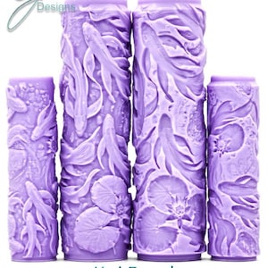 May include: Four cylindrical purple patterned rollers featuring an embossed design of koi fish, lily pads, and water lilies. The text G Designs, Koi Pond, and Intricate Texture is visible. The rollers vary in height and width, displaying a continuous relief pattern for surface texturing.