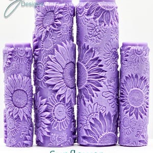 Op de afbeelding: Vier paarse, getextureerde deegrollers met een zonnebloemdessin. De deegrollers zijn in verschillende maten. De tekst "Sunflower Intricate Texture" staat onder de deegrollers.