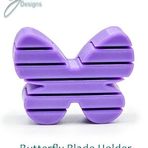 May include: Purple plastic butterfly-shaped blade holder.  The holder has a striped design.