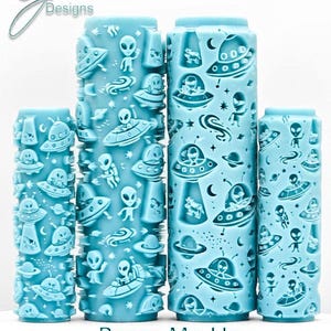 May include: A collection of five light blue cylindrical rollers with an alien and spaceship design. The rollers feature embossed images of aliens, UFOs, planets, and stars. The text "Beam Me Up Deep Impression" is at the bottom of the image.