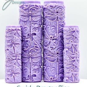 Peut inclure: Quatre cylindres lavande avec des motifs en relief de libellules et de fleurs. Les objets, de hauteurs différentes, sont regroupés. Le texte "Swirly Dragonflies Intricate Texture" est en bas de l'image.