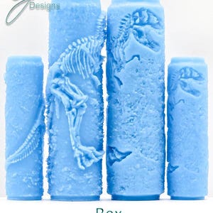 Puede incluir: Cuatro objetos cilíndricos de color azul claro con una superficie texturizada y un diseño de esqueleto de dinosaurio. El texto "Rex Deep Texture" está en la parte inferior. Los objetos varían en altura, el más alto con un esqueleto de T-Rex detallado.