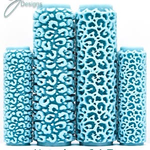 Peut inclure: Quatre rouleaux cylindriques bleu clair avec une texture en relief à motif léopard. Les rouleaux sont disposés en rangée avec deux plus grands au centre et deux plus courts sur les côtés. Le texte G Designs, Notorious C.A.T. Deep Impression est visible.