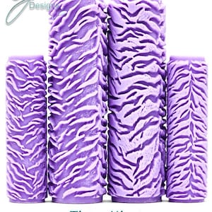 Puede incluir: Cuatro rodillos de pintura de color morado con un patrón en relieve de rayas de tigre. Los rodillos están dispuestos en fila con dos más altos en el centro y dos más cortos a los lados. El texto G Designs, Tiger King e Intricate Texture es visible.