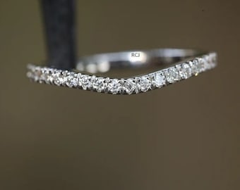 May include: A delicate, curved wedding band with a row of small, sparkling diamonds.