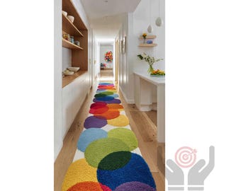 Pode incluir: Um longo corredor com um tapete colorido com círculos sobrepostos em tons de vermelho, laranja, amarelo, verde, azul e roxo. O tapete está sobre um chão de madeira e as paredes são brancas.