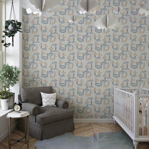 May include: A nursery with wallpaper patterned with blue and orange fish and aquatic plants. The room features a grey armchair, a white cot, and cloud-shaped decorations. The room has wooden flooring.