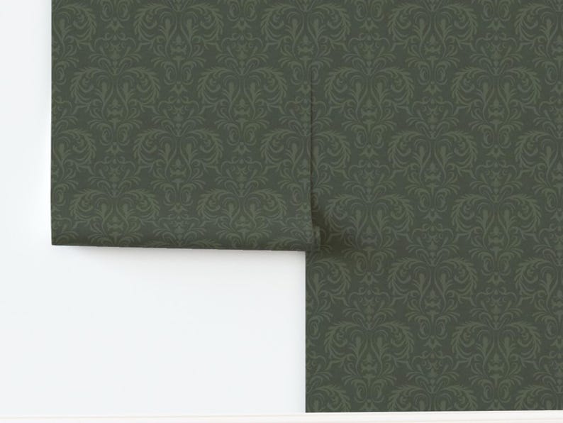 A dark green rectangular panel of fabric or wallpaper features a repeating damask pattern in a slightly lighter green. The symmetrical floral and scroll motifs are intricately detailed, creating a subtle contrast. The surface looks smooth with no visible texture variation. The straight edges suggest standard cut dimensions.