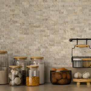 May include: A kitchen scene featuring a light-colored brick backsplash. Glass jars with wooden lids hold various ingredients, including garlic, spices, and sugar. A wire basket contains eggs, and a small wooden stand displays garlic bulbs.