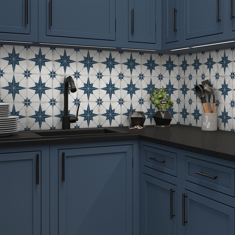 May include: A kitchen with blue cabinets and black countertops. The backsplash is white tile with a blue star pattern. A black faucet is mounted above a black sink. There is a small plant in a pot on the counter.