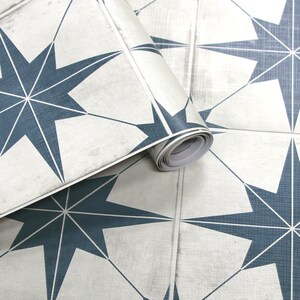 May include: Roll of self-adhesive vinyl wallpaper with a repeating pattern of blue starburst shapes on a white background.