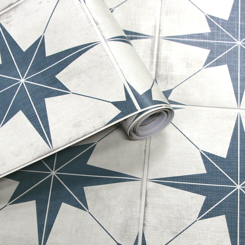 May include: Roll of self-adhesive vinyl wallpaper with a repeating pattern of blue starburst shapes on a white background.