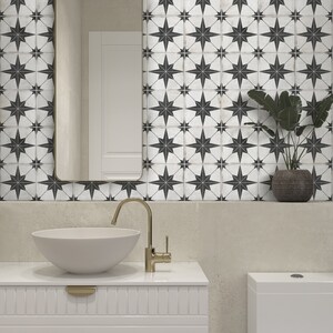 May include: A white bathroom with black and white star-shaped tile, a white porcelain sink with a gold faucet, and a white toilet.