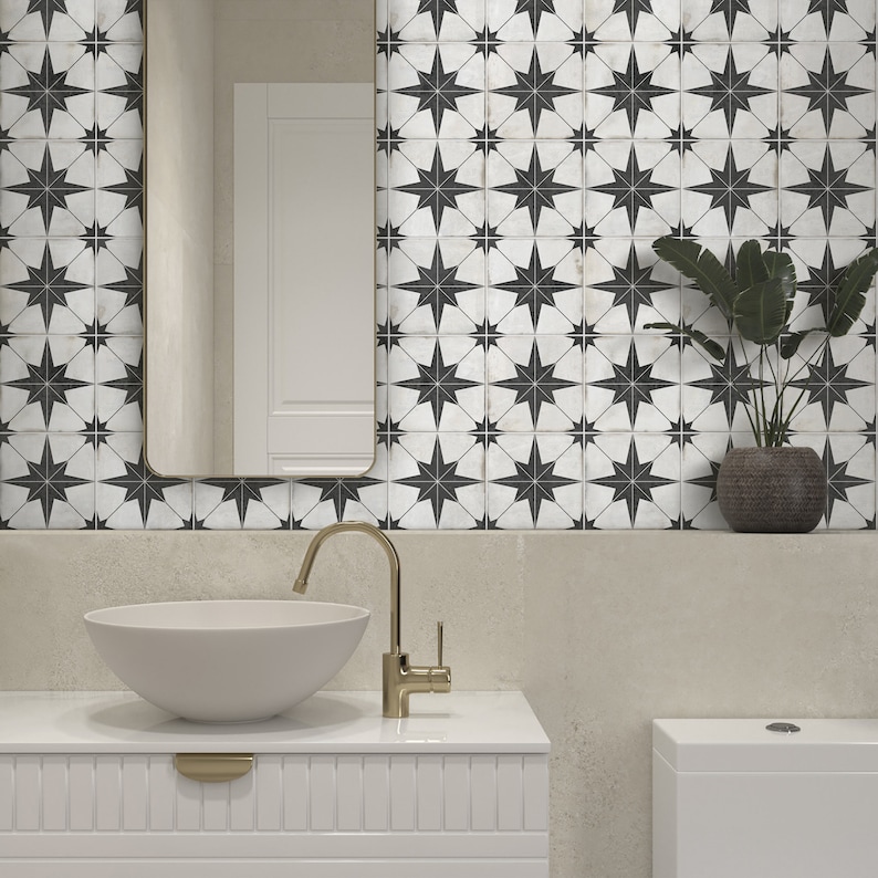 May include: A white bathroom with black and white star-shaped tile, a white porcelain sink with a gold faucet, and a white toilet.