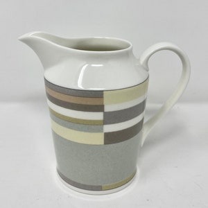 May include: A white ceramic jug with a geometric pattern in shades of brown, beige, and grey.