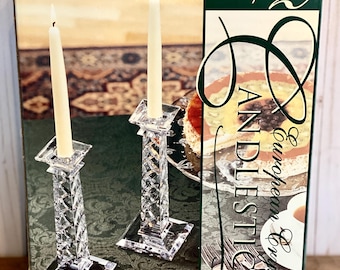 Könnte beinhalten: Ein Set aus zwei europäischen Kristall-Kerzenständern in einer Schachtel. Die Kerzenständer sind klar und haben ein Diamantenmuster. Die Schachtel ist weiß mit grünen und goldenen Akzenten. Der Text auf der Schachtel lautet "Set of 2 European Crystal Candlesticks".