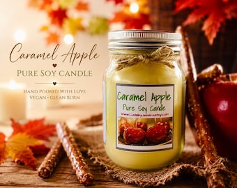 Puede incluir: Una vela en frasco de vidrio transparente con cera de color amarillo pálido, tapa de metal plateado y un lazo de cuerda. La etiqueta muestra el texto Caramel Apple Pure Soy Candle y una imagen de manzanas de caramelo sobre una superficie de madera.