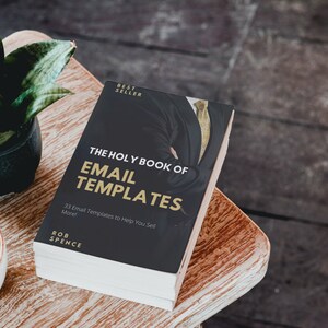 Könnte beinhalten: Ein schwarzes Buch mit goldenen Lettern mit dem Titel "The Holy Book of Email Templates" mit dem Untertitel "33 Email Templates to Help You Sell More!" von Rob Spence. Das Buch liegt auf einer Holzoberfläche.