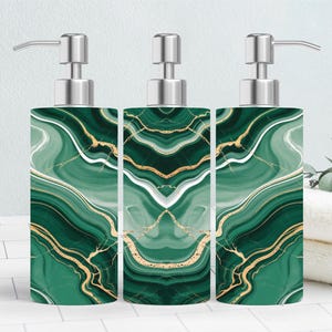 May include: Three decorative soap dispensers with a green and gold marble design. Each dispenser has a silver pump and a rectangular shape. The marble pattern features swirling green and gold veins.