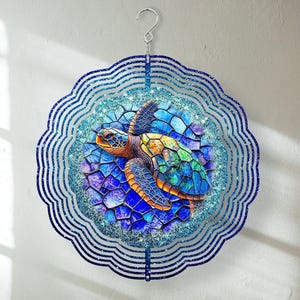 May include: A blue and green metal wind spinner with a mosaic-style sea turtle design. The spinner has multiple layers of metal that spin in the wind.