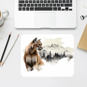 May include: A brown and tan cougar with a white chest sits in a snowy mountain landscape. The cougar is looking to the right of the image. The background is a watercolor painting of a mountain range with trees and snow.