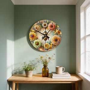 May include: A round wall clock featuring a central illustration of a bee surrounded by a wreath of colorful dahlias in shades of yellow, orange, and pink. The clock face has black numbers from 1 to 12 and black hour, minute, and second hands.