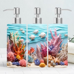 May include: Three square soap dispensers with a vibrant underwater scene. The design features colorful coral, white fish, and a light blue background. Each dispenser has a silver pump.