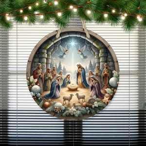 May include: A round Christmas wall hanging depicting the Nativity scene. The artwork features Mary, Joseph, baby Jesus, angels, and shepherds. The wooden frame is decorated with greenery and a hanging rope. The background shows a star and a snowy landscape.