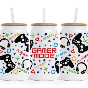 May include: Three white gamer-themed tumblers with a bamboo lid and a straw. The tumblers feature a black and white design of a video game controller, headphones, and the words "Gamer Mode", "Player", and "Gamer".