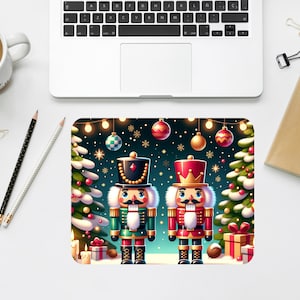 May include: A Christmas-themed mousepad featuring two nutcracker figures in festive attire. One nutcracker wears a green and gold uniform, the other a red and gold uniform. The background includes Christmas trees, ornaments, and string lights.