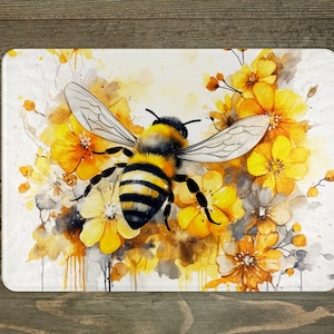May include: A watercolor painting of a bee with black and yellow stripes, surrounded by yellow flowers with white centers. The bee is flying towards the viewer with its wings spread out. The background is a white canvas with watercolor splatters.