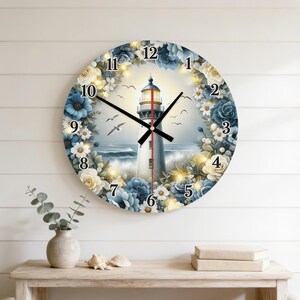 May include: A round wall clock featuring a central lighthouse illustration surrounded by a wreath of blue and cream-colored flowers. The clock face displays black numbers from 1 to 12, black hour and minute hands, and a thin red second hand.