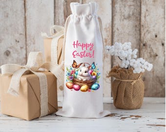 May include: White fabric wine bag with a drawstring closure. The bag features a colorful illustration of a bunny rabbit in a basket with Easter eggs and butterflies. The text "Happy Easter!" is printed in pink letters.