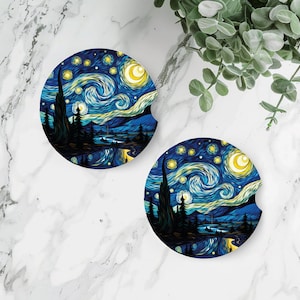 May include: Two round, white coasters with a blue and yellow starry night design. The design is reminiscent of Vincent van Gogh's famous painting.