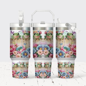 May include: White stainless steel tumbler with a floral and frog design. The tumbler has a lid with a straw and a handle.