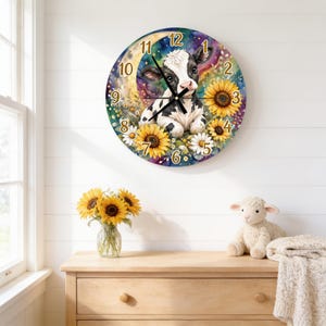 May include: A round wall clock featuring a black and white calf illustration surrounded by yellow sunflowers and white daisies against a colorful, starry background. The clock face displays gold-colored numbers from one to twelve and black hands.