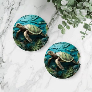 May include: Two round coasters with a blue ocean background and a green sea turtle swimming in the water. The turtle is surrounded by coral and fish.
