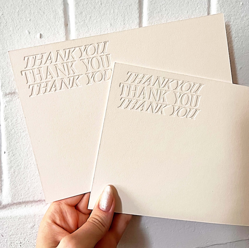 以下が含まれることがあります： クリーム色の背景に白いエンボス加工で「Thank You」という文字が書かれた、空白のカードが2枚です。