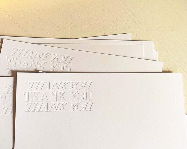 以下が含まれることがあります： 各カードに「THANK YOU」というエンボス加工が施された白いサンキューカードの束