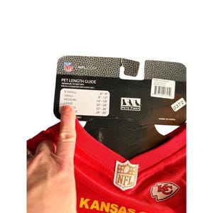 May include: A red Kansas City Chiefs pet jersey with the NFL logo and team logo. The jersey has a size guide for pet length, ranging from X-Small (6-9 inches) to Large (20-24 inches).